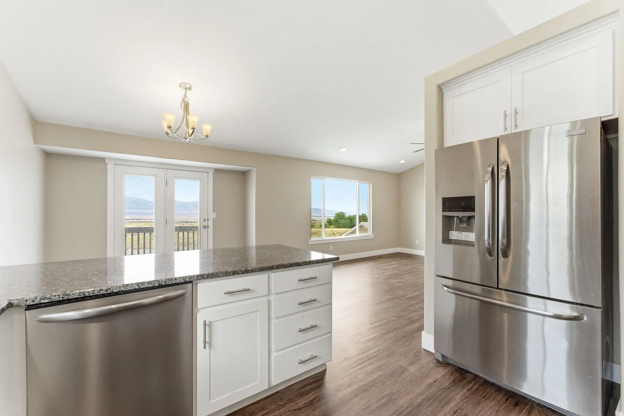 Kitchen island featuring a speckled countertop, white cabinetry, and stainless steel dishwasher