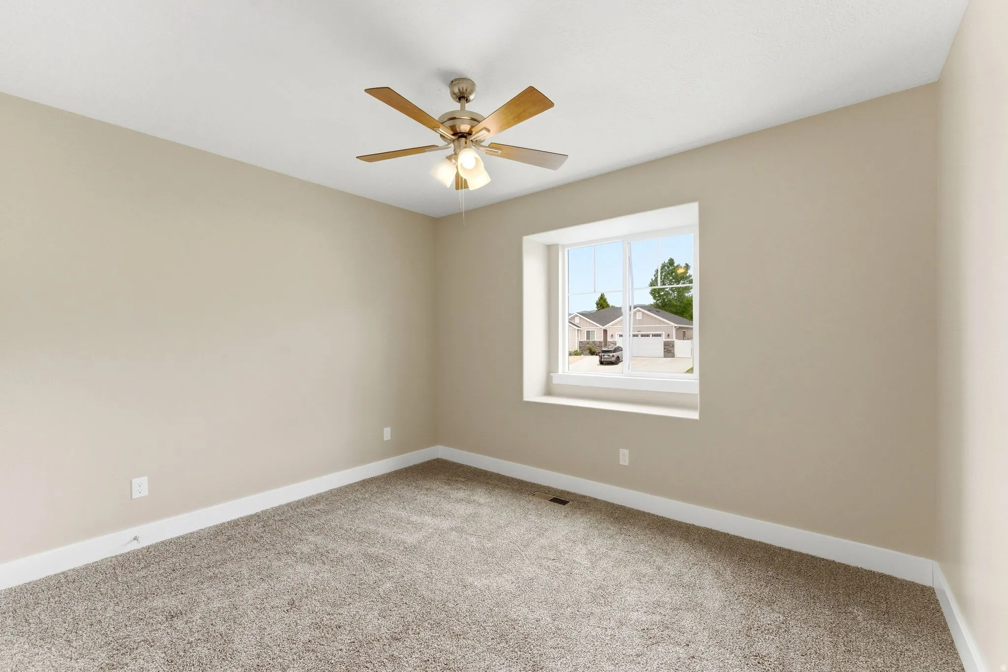 Carpeted room featuring a ceiling fan with light fixture, neutral wall finishes, white trim, and a prominent window