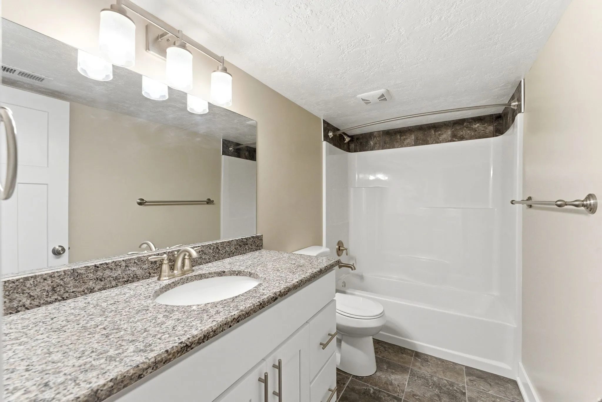 Basement bathroom featuring a white vanity with brushed nickel hardware, a light granite countertop with an undermount sink, and a large mirror