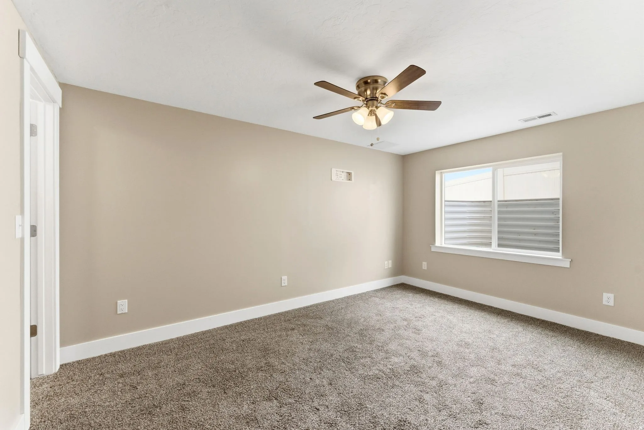 Neutral-toned interior room featuring brown carpet flooring, beige painted walls, and white baseboards