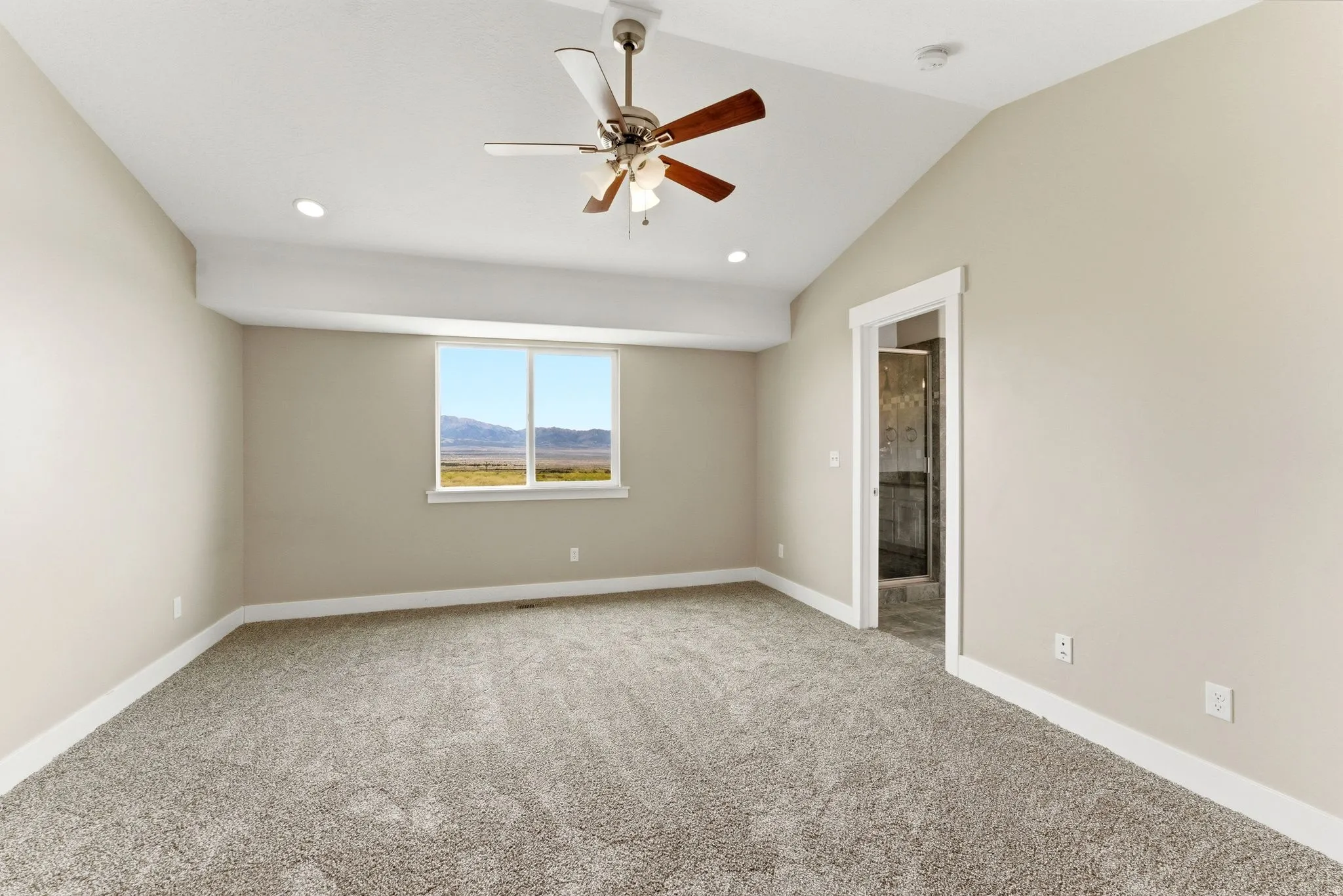 Carpeted room featuring a vaulted ceiling with a ceiling fan, recessed lighting, and a large window