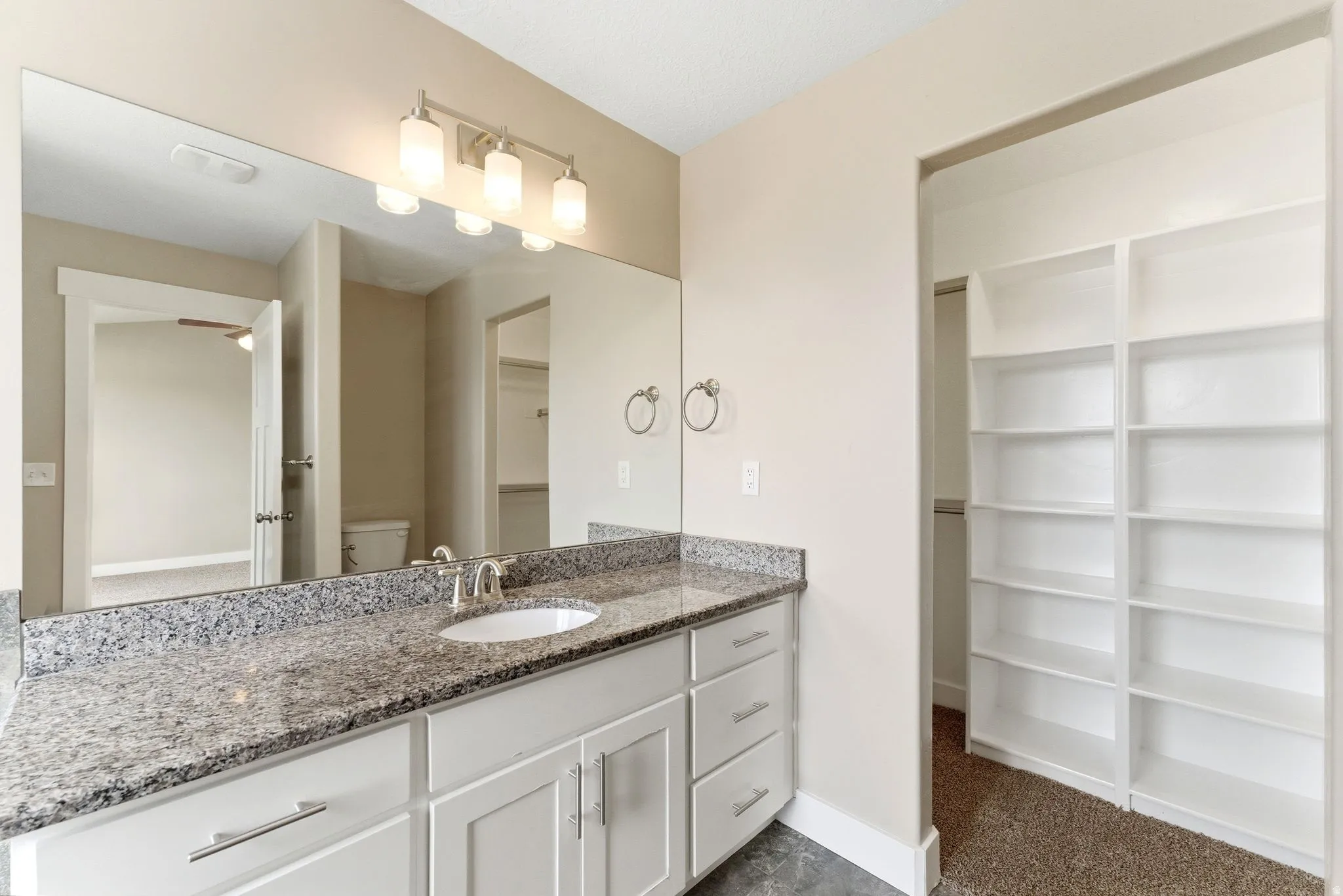Bathroom vanity featuring an integrated sink, polished chrome faucet, and stone countertop