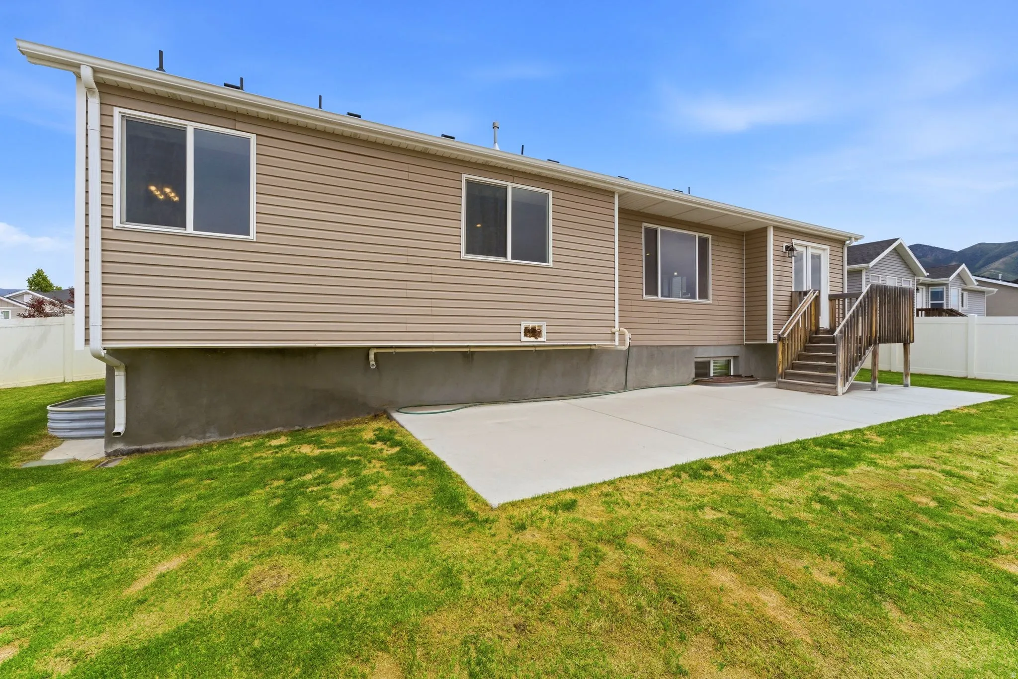 Rear exterior showcasing beige horizontal siding and a concrete patio