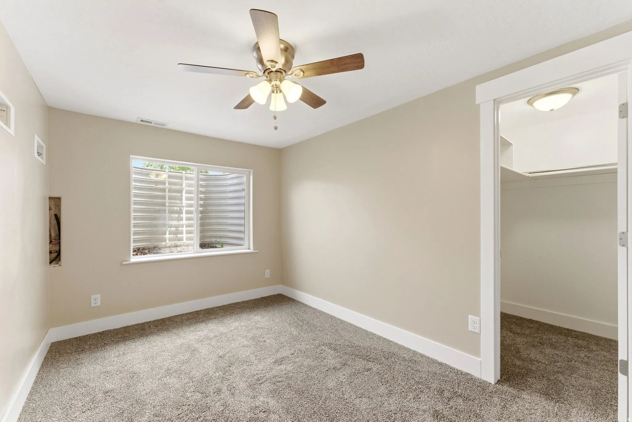 Room featuring neutral wall tones, textured carpet flooring, and a ceiling fan with integrated lighting