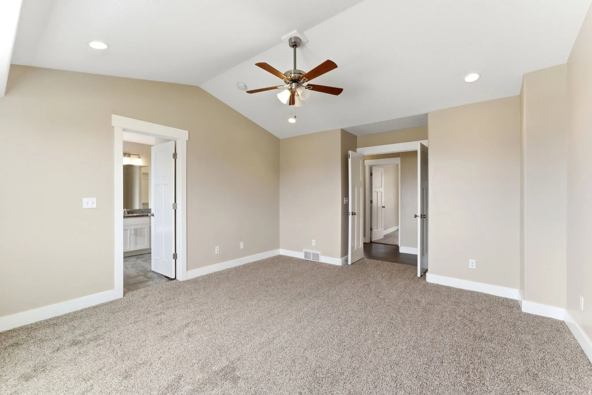 Spacious carpeted room featuring a vaulted ceiling with a ceiling fan, recessed lighting, and neutral wall tones