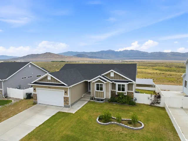 Single-story home featuring a two-car garage, manicured front lawn, and stone accent siding