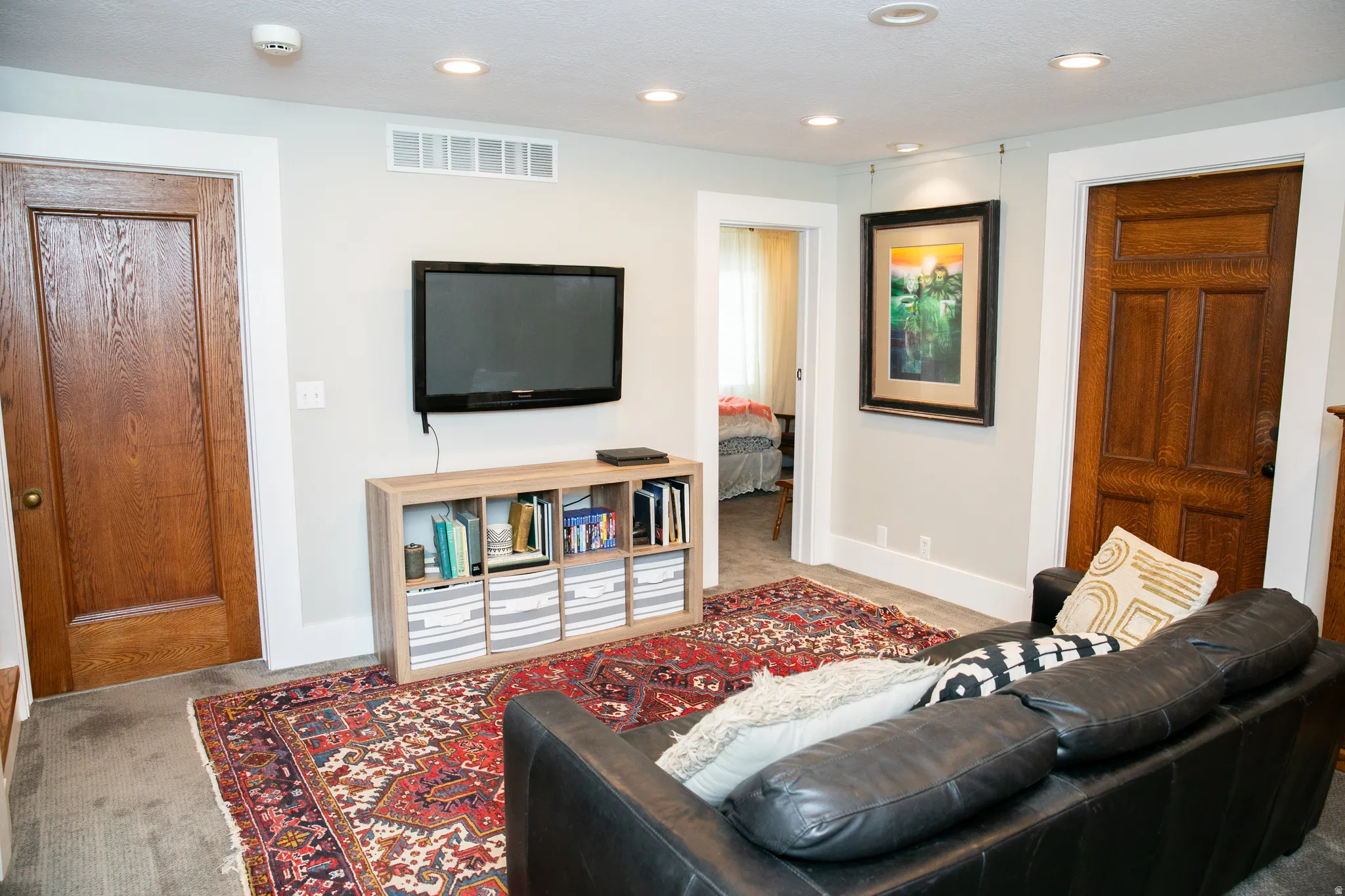 Recessed ceiling lighting illuminates a room featuring light gray walls, white trim, and two paneled wood doors