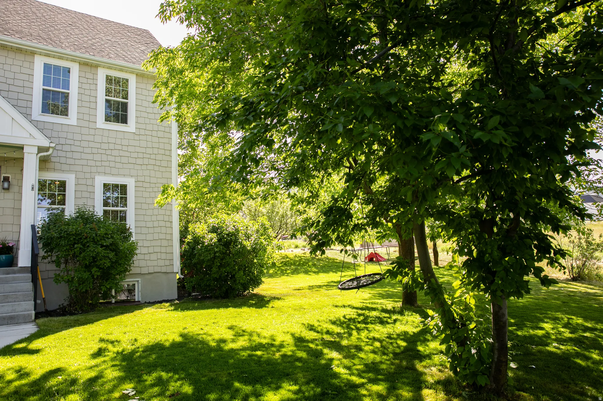 Expansive green lawn featuring mature trees providing natural shading