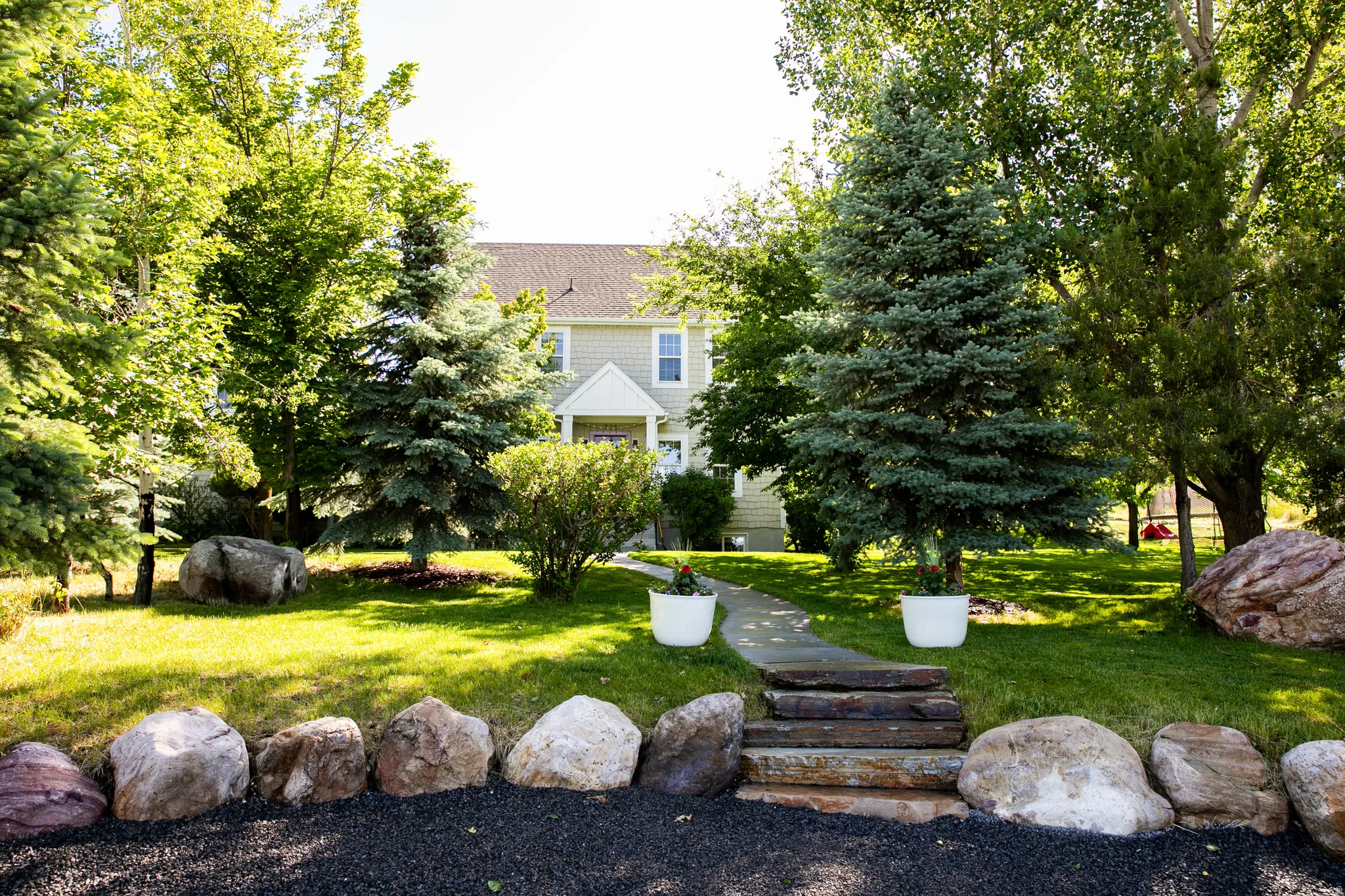 Manicured lawn with mature trees and natural stone landscaping