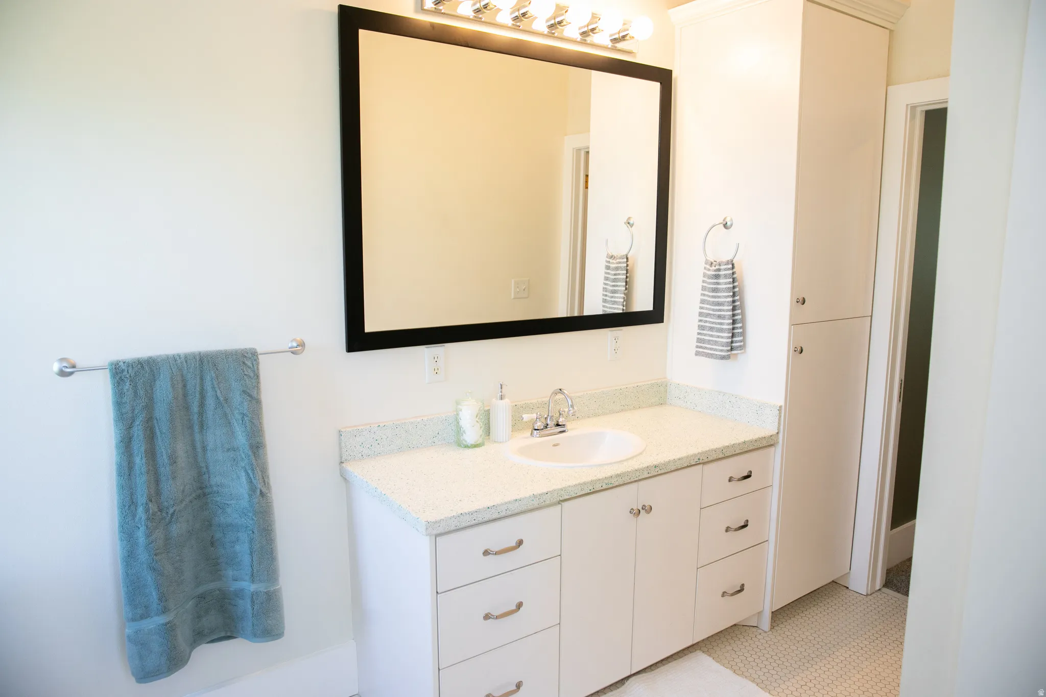 Bathroom featuring a white vanity with an integrated sink, polished chrome faucet, and speckled countertop