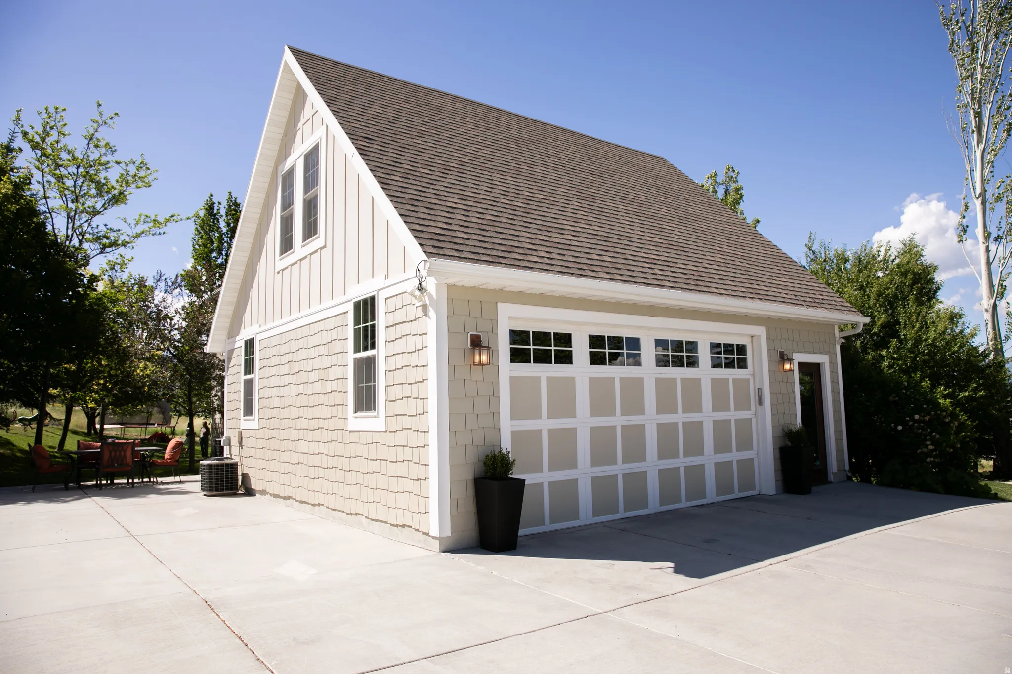 Detached garage structure featuring a hip-and-gable roofline, shingle siding, and board and batten accents