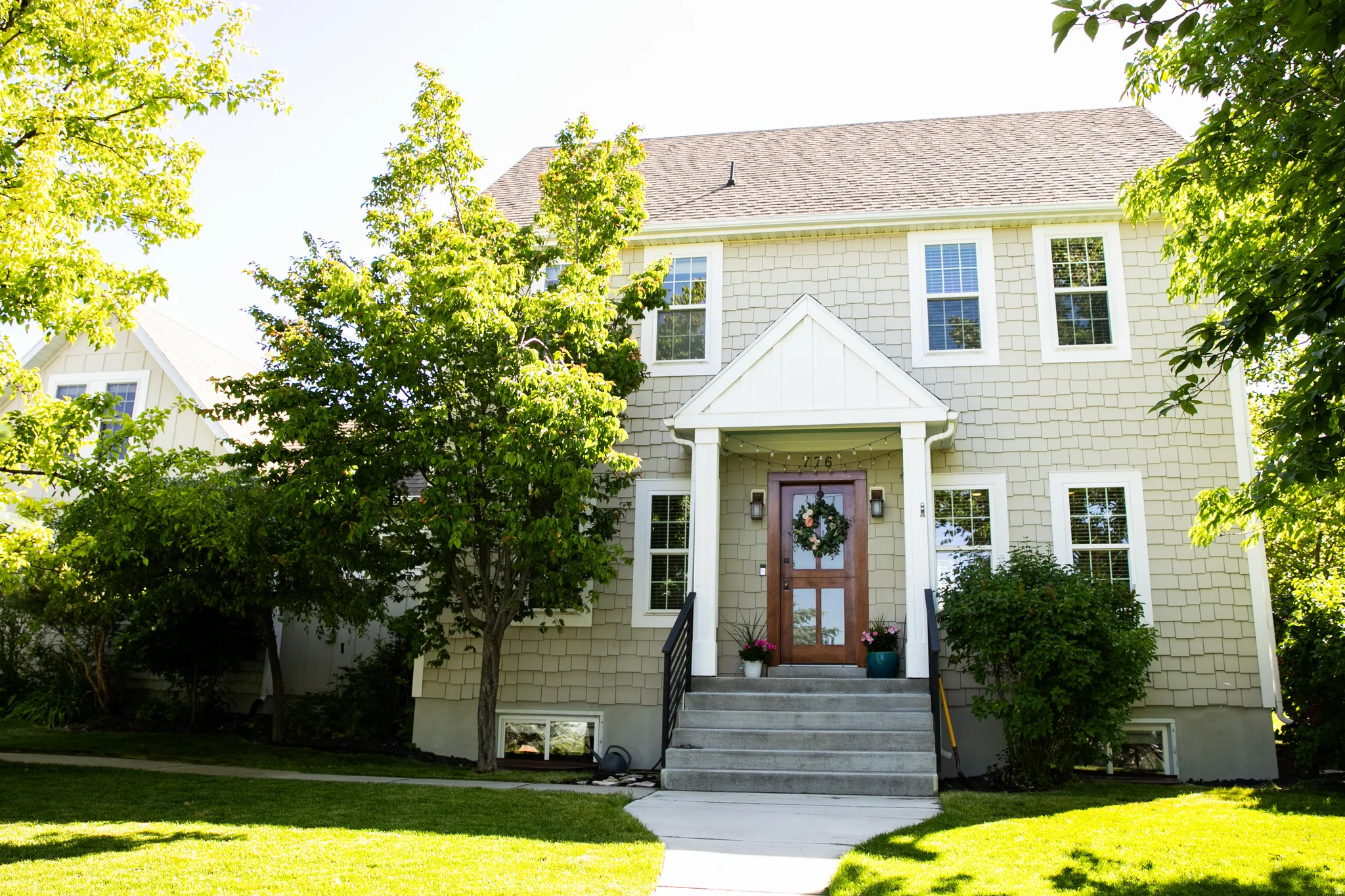 Two-story residence featuring light-colored shingle siding and a prominent gable-covered entry