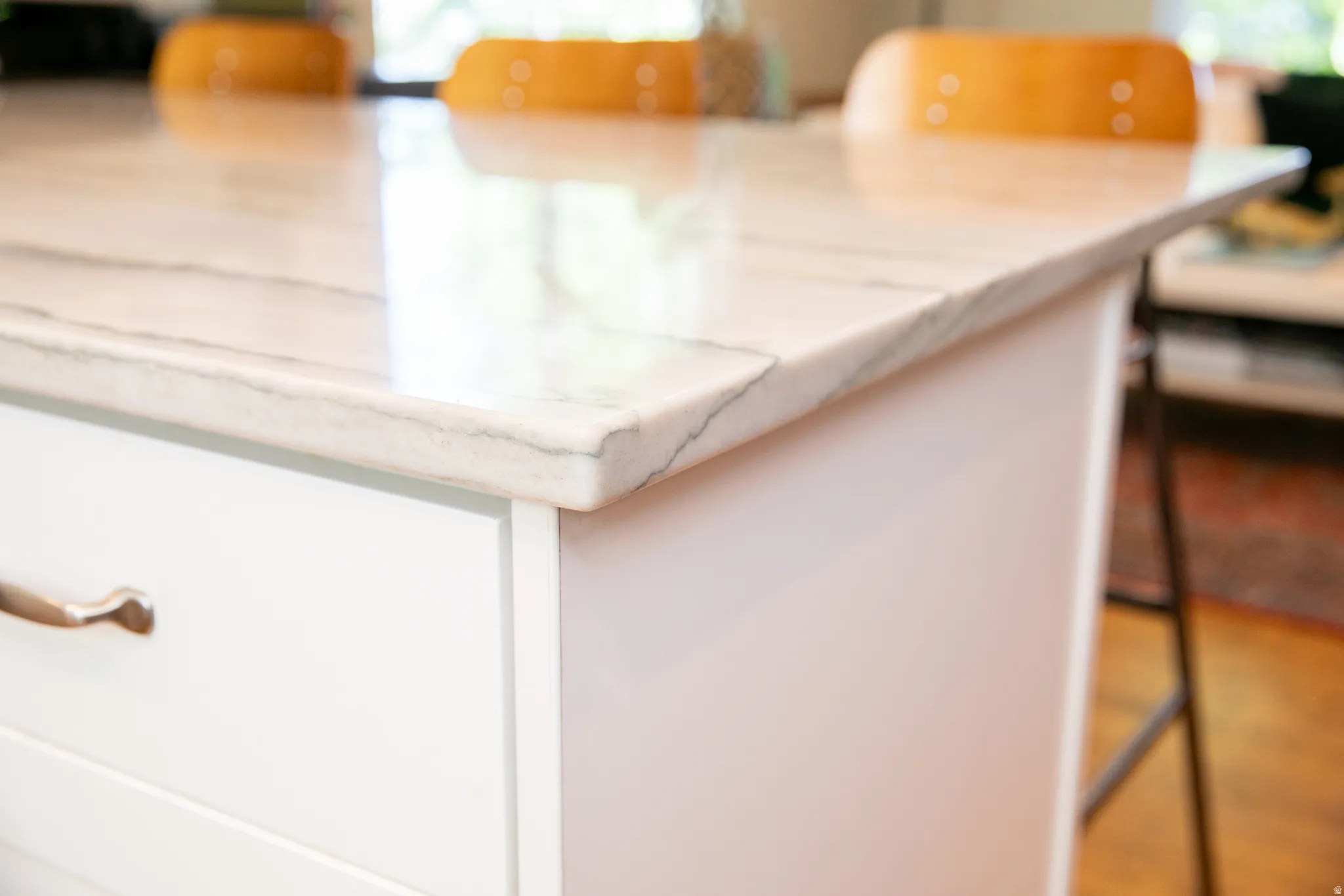 Kitchen island featuring a veined stone countertop with an eased edge, white shaker-style cabinetry, and brushed nickel hardware