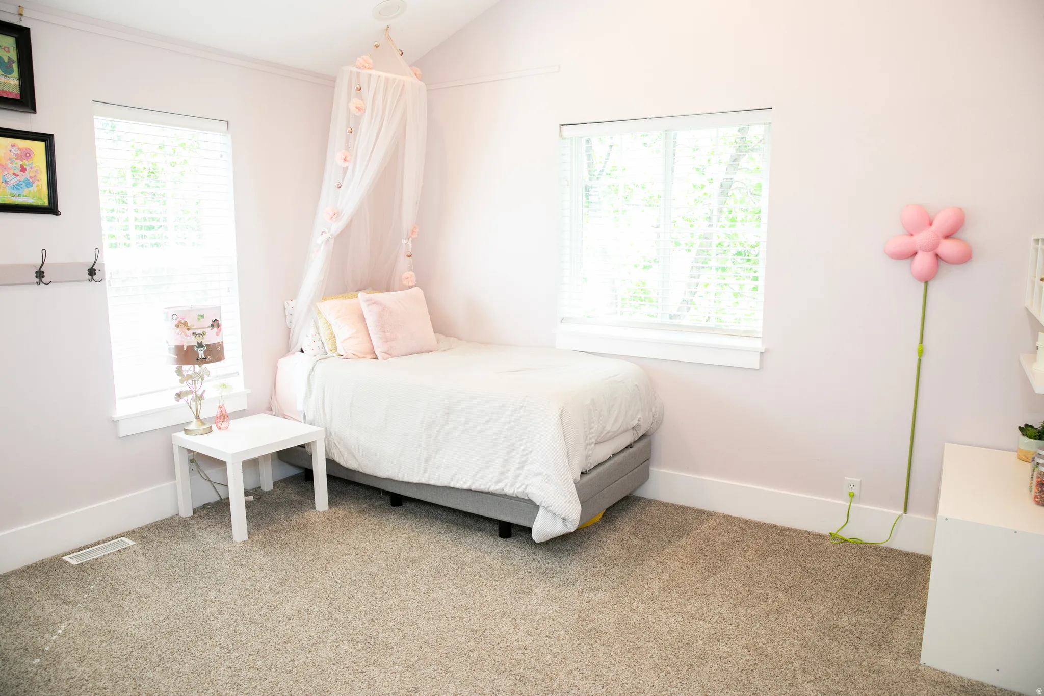 Bright interior space featuring two windows with white blinds, neutral carpeting, and a vaulted ceiling