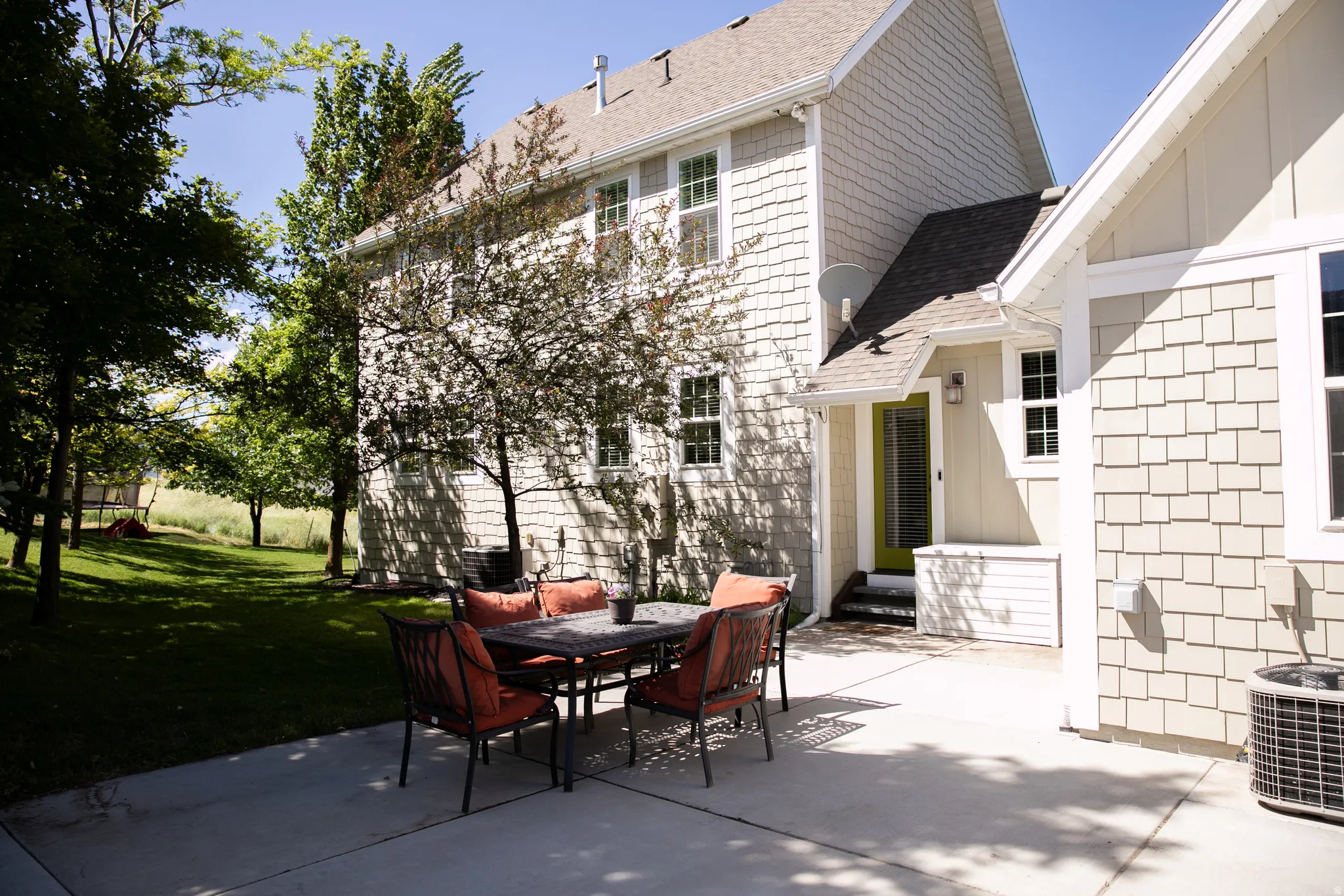 Spacious concrete patio with a natural grass yard and mature trees