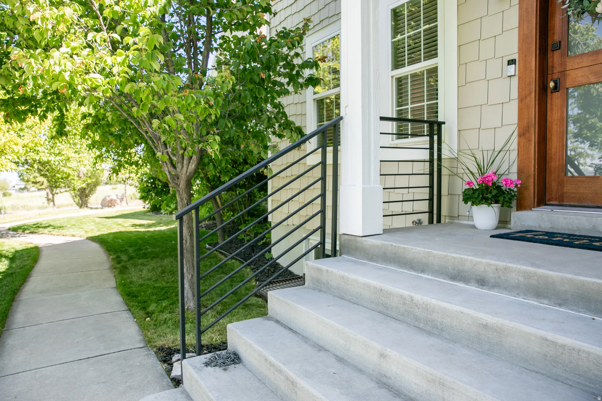 Concrete steps with contemporary metal railings lead to a wooden front door
