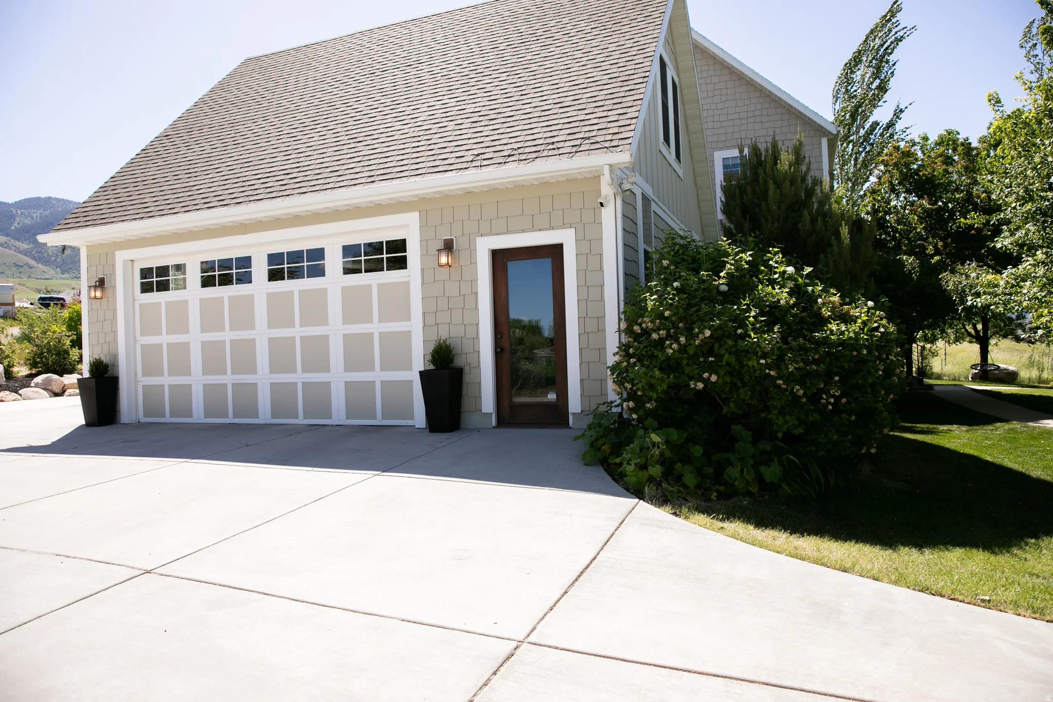 Attached garage with panel-style door, upper window inserts, and sconce lighting