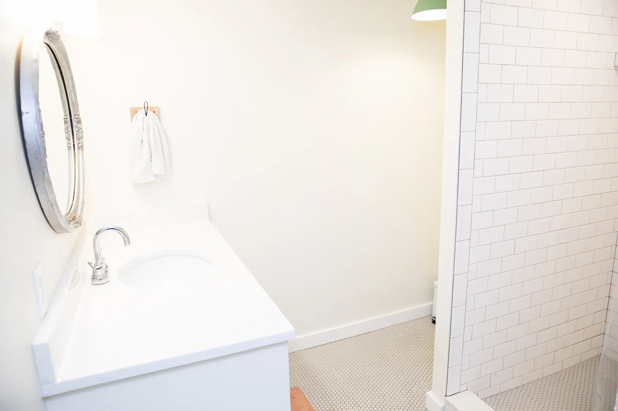 Bathroom featuring a white vanity with an integrated sink, polished chrome faucet, and an oval mirror with a decorative frame