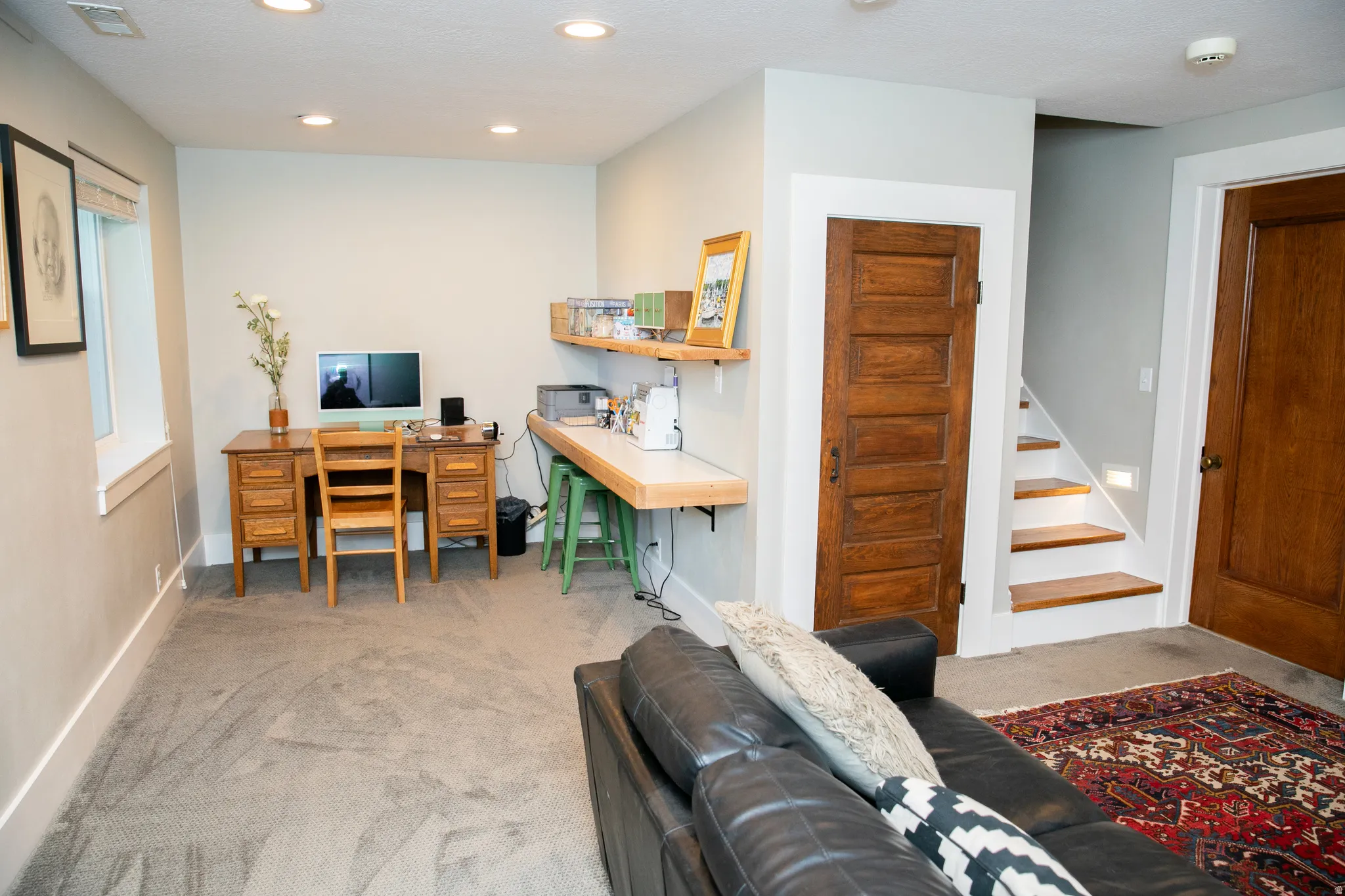 Carpeted living space featuring recessed lighting, a built-in wood-finish desk, and a built-in light wood-finish countertop with open shelving