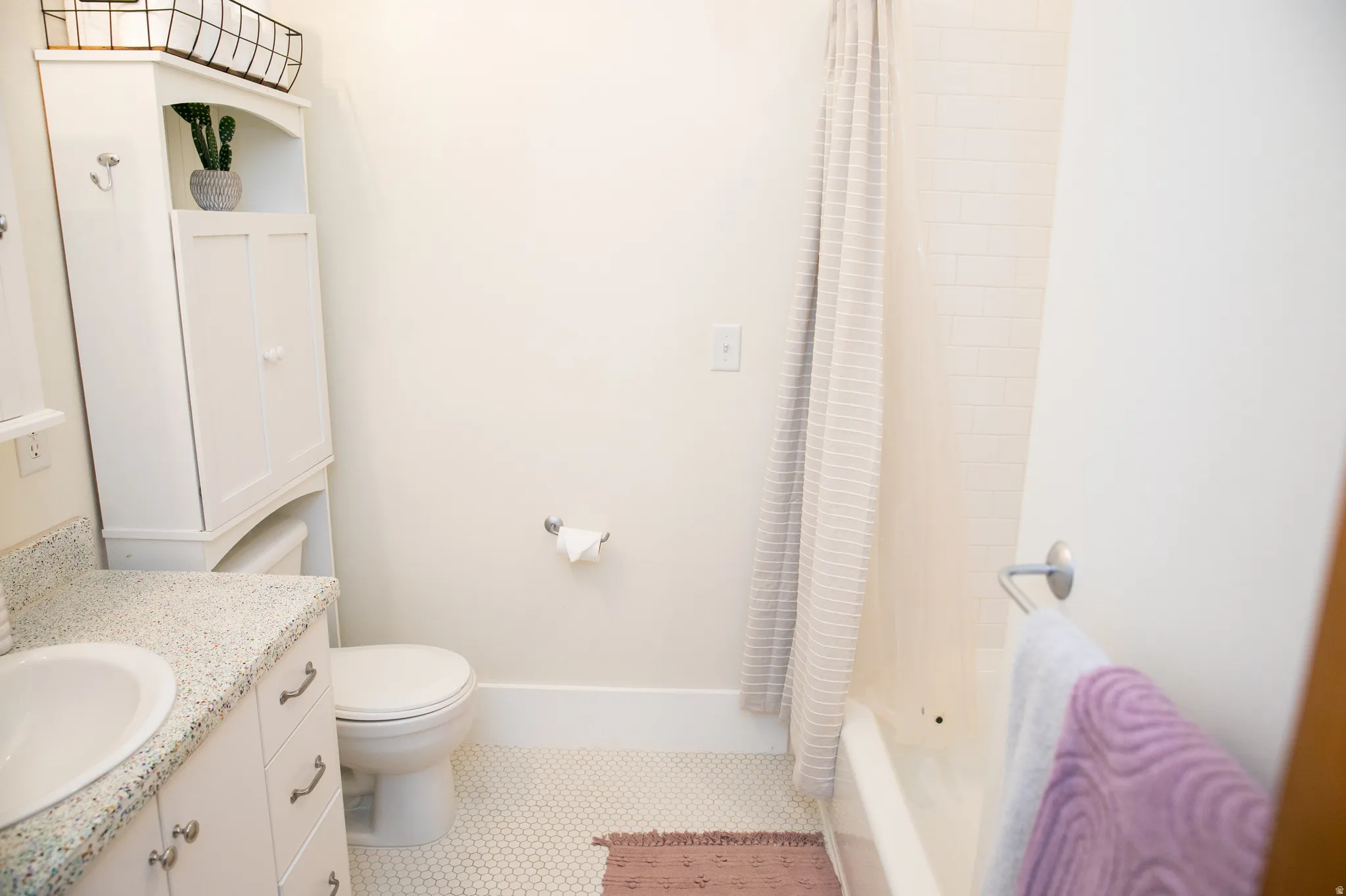 Bathroom featuring a white vanity with a speckled countertop and an undermount sink