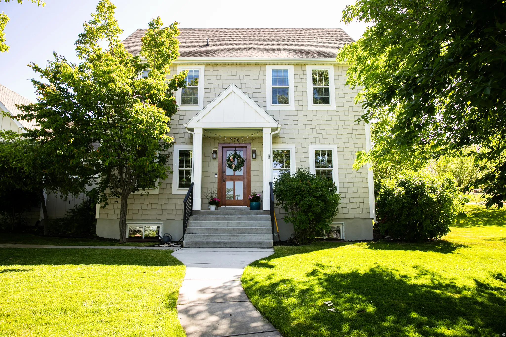 Two-story residence featuring light-colored shingle siding and a gabled entry porch