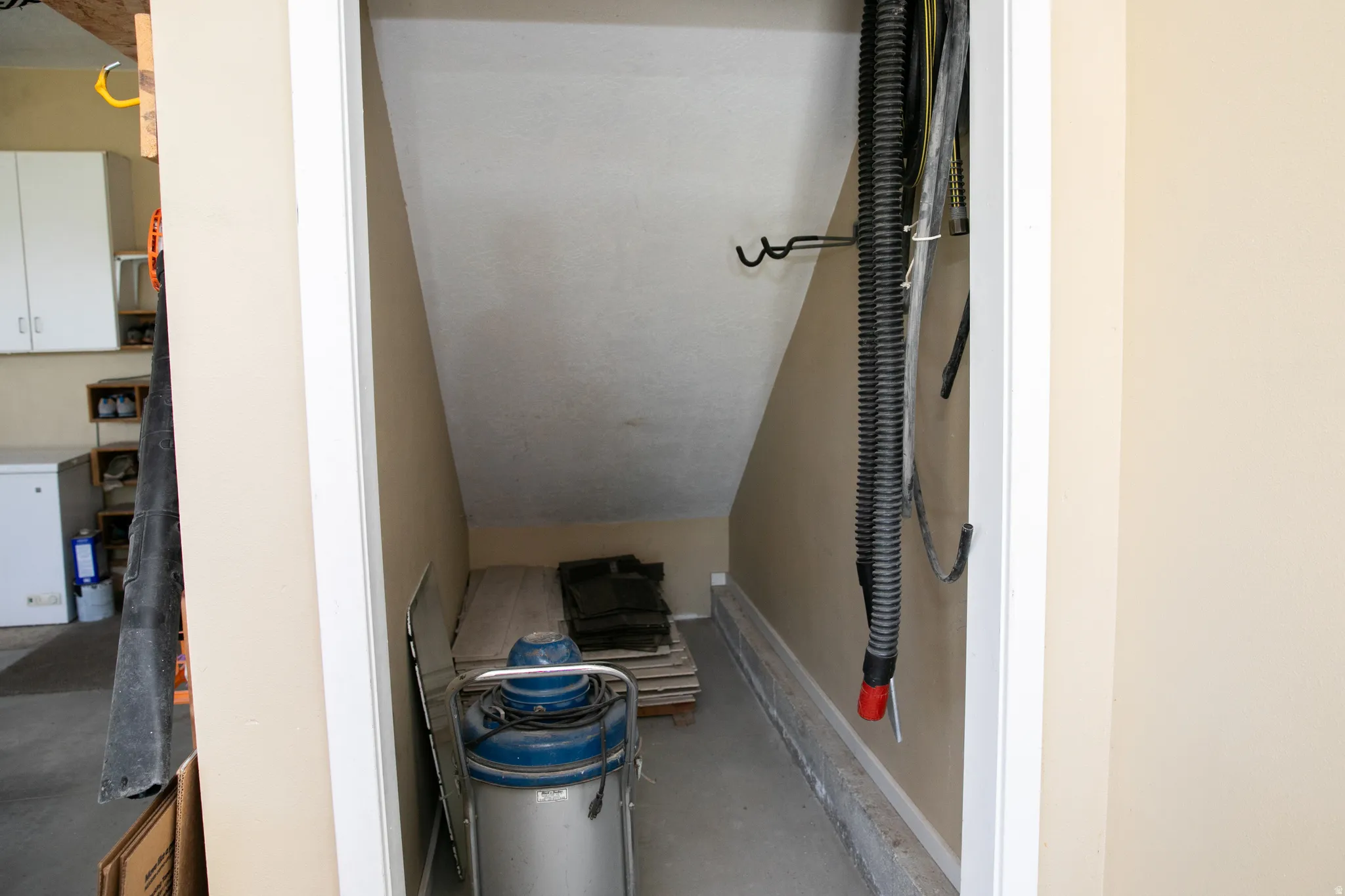 Under-stair storage area with concrete flooring and neutral-toned walls