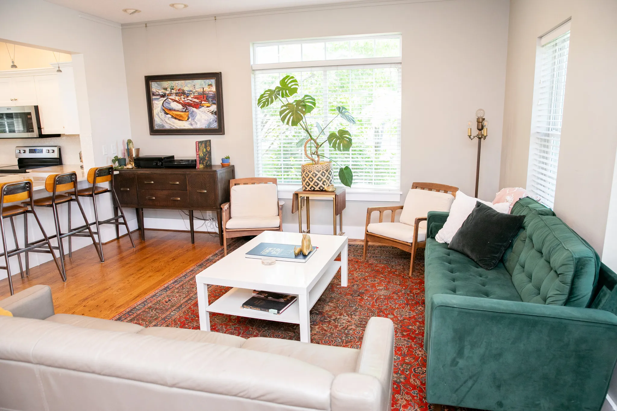 Open-concept living area featuring wood-finish flooring, a pass-through kitchen counter, and multiple windows with blinds