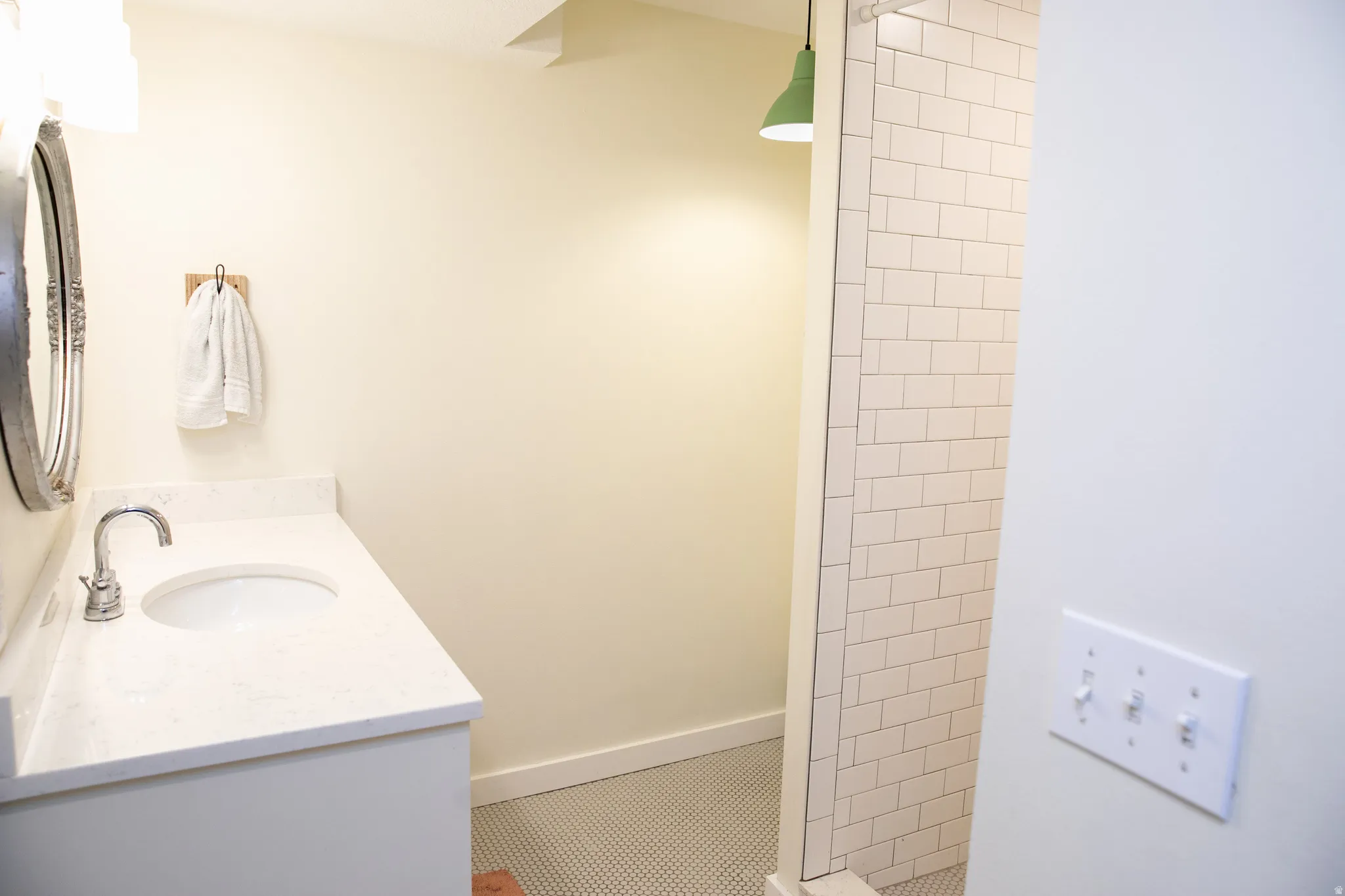 Bathroom vanity featuring a polished chrome faucet, white countertop, and a decorative framed mirror