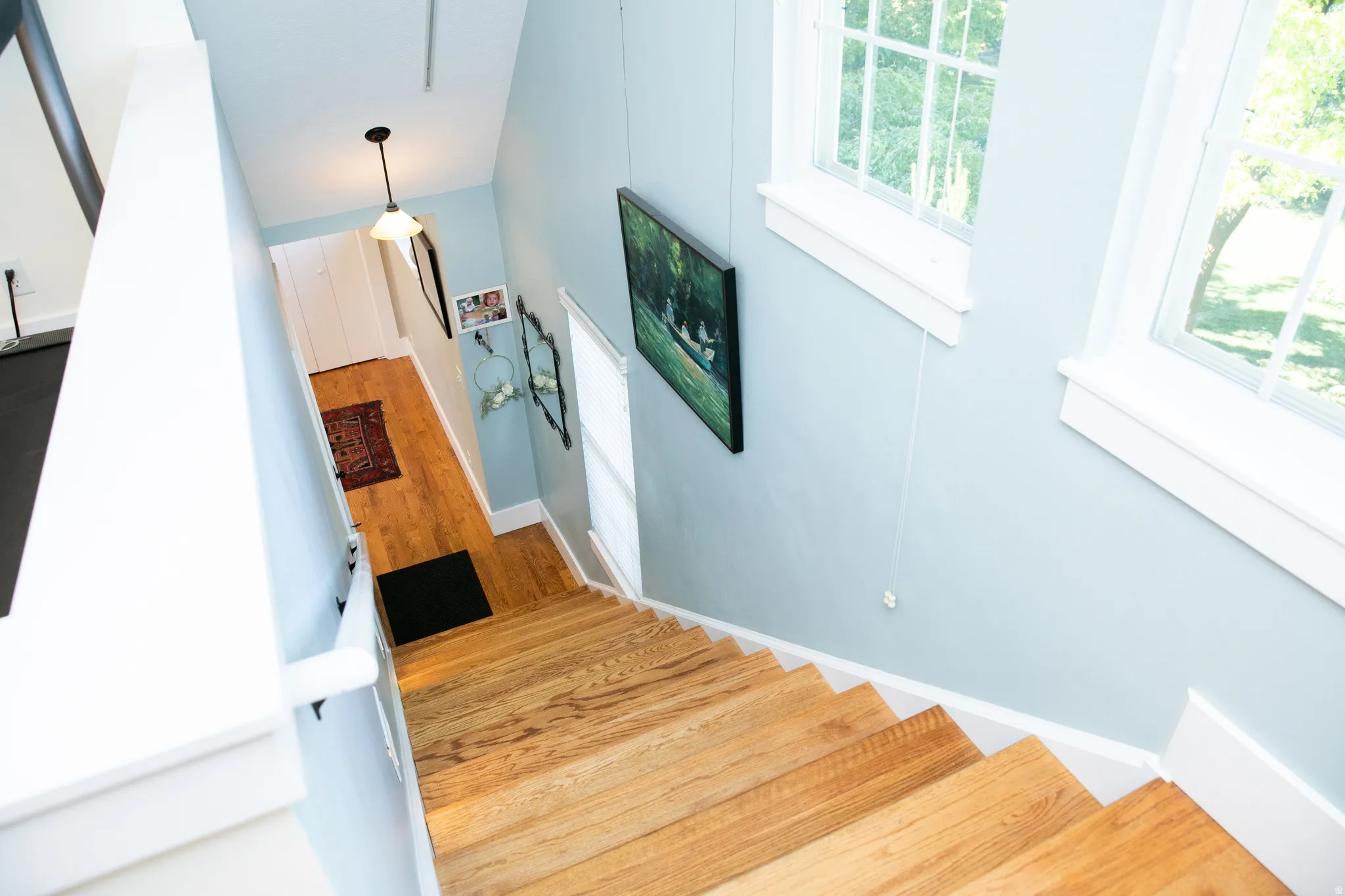 Hardwood staircase with white risers and handrail, paired with a light blue wall