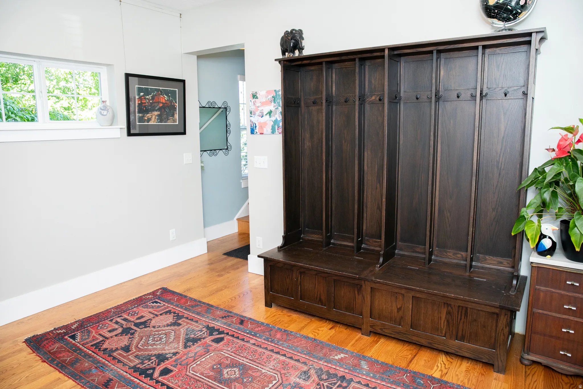 Built-in wood-finish hall tree with integrated storage and coat hooks, complemented by hardwood flooring and light-toned walls