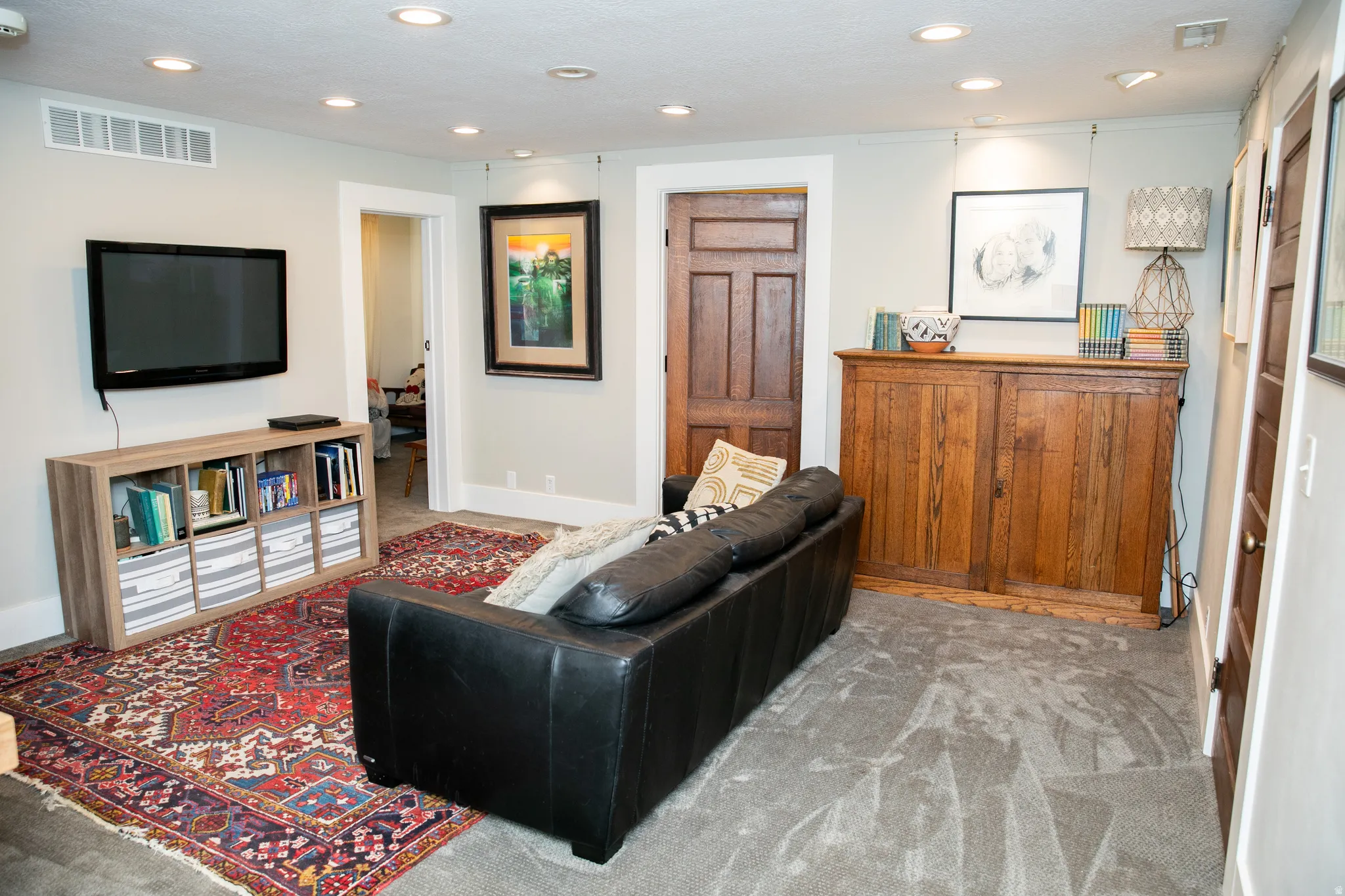 Recessed lighting illuminates this room featuring light-toned walls and contrasting dark wood-panel doors