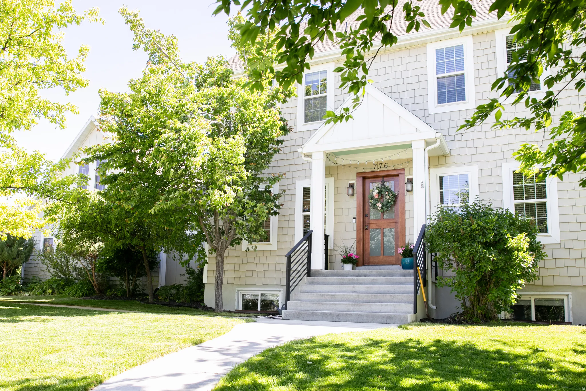Shingle-sided exterior featuring a covered porch entry, a paneled wood front door with sidelights, and a concrete pathway