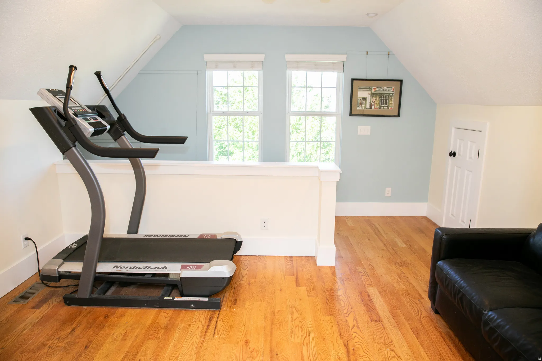 Finished bonus room featuring hardwood flooring, multiple windows, and a built-in half-wall partition