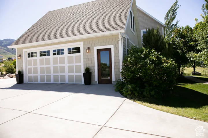 Attached garage with panel-style door, upper window inserts, and sconce lighting