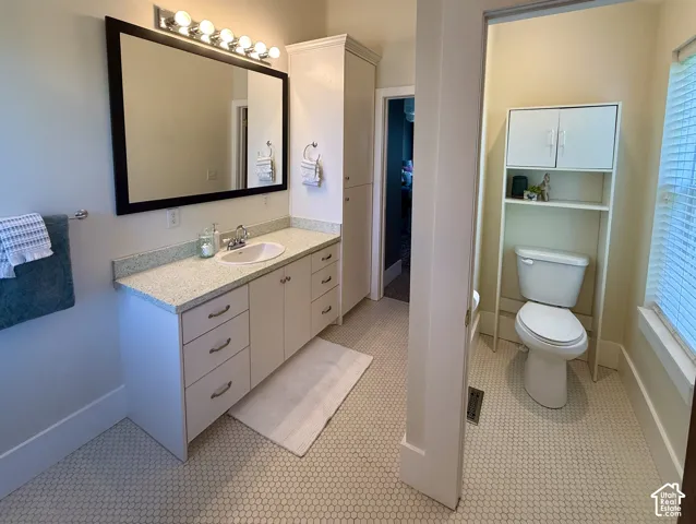 Primary Bathroom featuring a white vanity with an undermount sink, a countertop with light flecking, and a large framed mirror with overhead lighting
