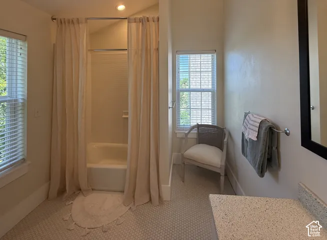 Primary Bathroom featuring a tub/shower combination with tile surround, a window with horizontal blinds, and mosaic tile flooring