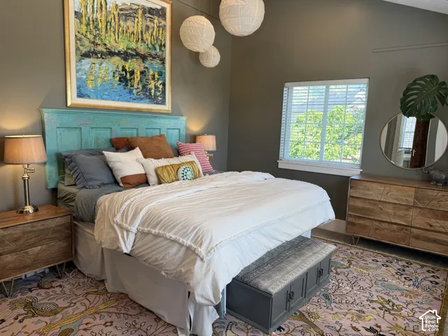 Vaulted ceilings and large windows illuminate this Primary Bedroom, featuring a unique teal headboard.