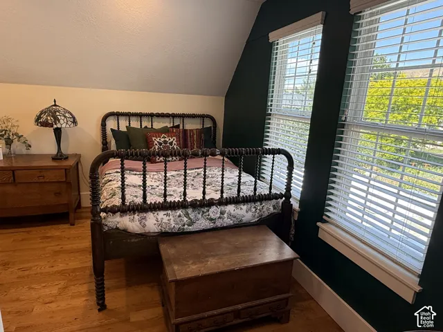 Bedroom #6 featuring two windows with horizontal blinds, hardwood flooring.