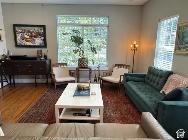 Hardwood flooring throughout featuring multiple windows with blinds, a built-in wall niche, and crown molding