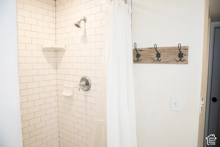 Shower stall featuring white subway tile, a built-in corner shelf, and a chrome shower head and controls