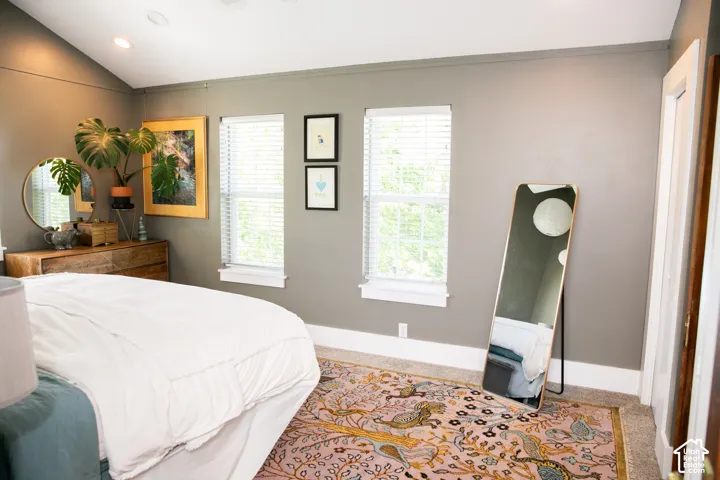 Primary Bedroom featuring vaulted ceilings, recessed lighting, and two windows with blinds.