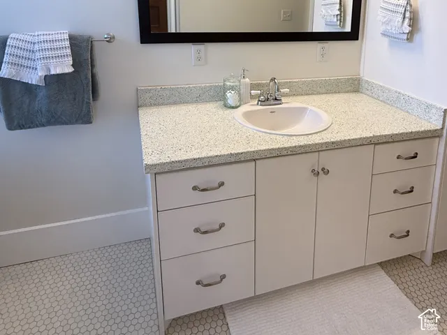 Primary Bathroom vanity featuring a white undermount sink, speckled countertop, and white cabinetry with brushed nickel hardware