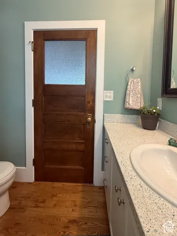 Main floor bathroom with wood-finish flooring complementing a rich wood door with privacy glass panel