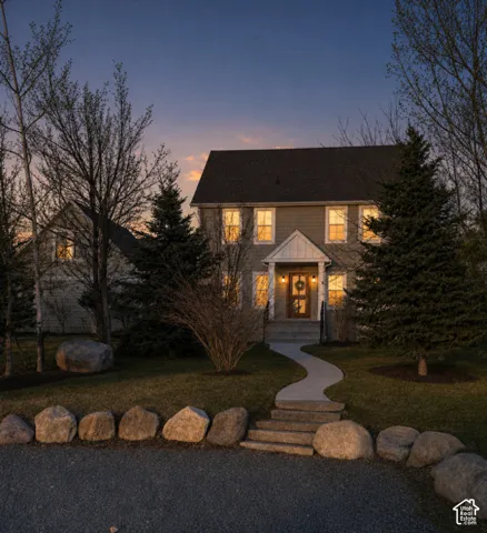 Shingled exterior with a prominent front entrance, concrete walkway, and stone retaining wall