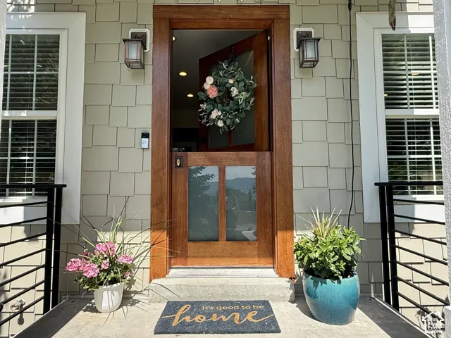 Warm wood-paneled entry door with glass panels, flanked by two bronze-finish exterior sconces