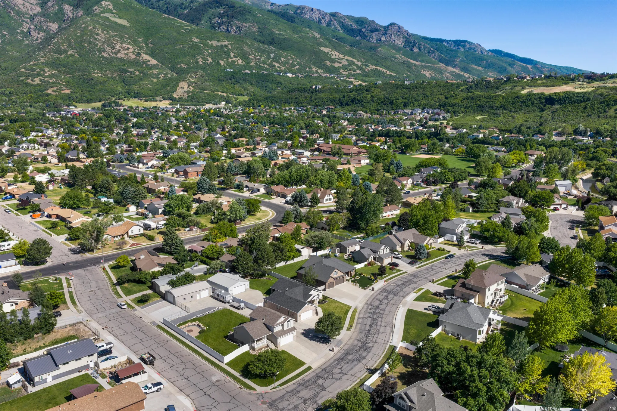 Residential neighborhood with mature trees and paved streets, framed by a prominent mountain range