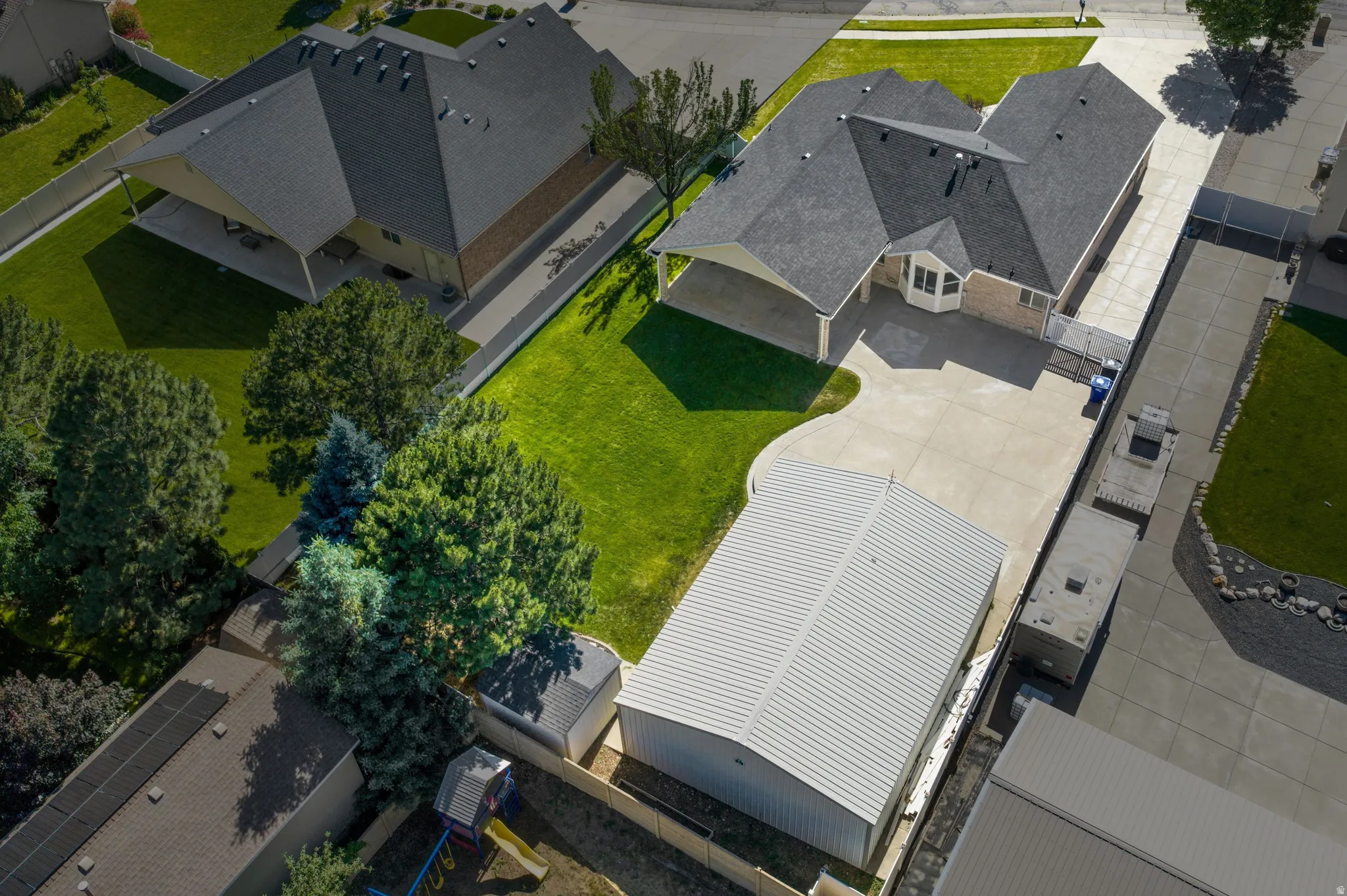 Expansive paved driveway leading to a two-story residence with an attached garage and a separate garage shop. RV Parking.
