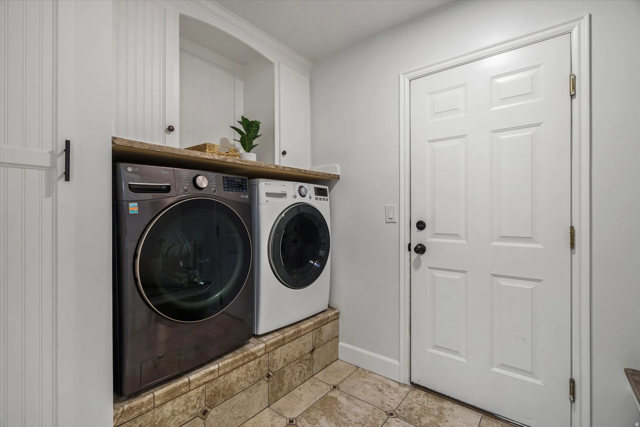 Dedicated utility area featuring a front-loading washer and dryer, integrated countertop, and upper cabinetry MUD ROOM off of garage
