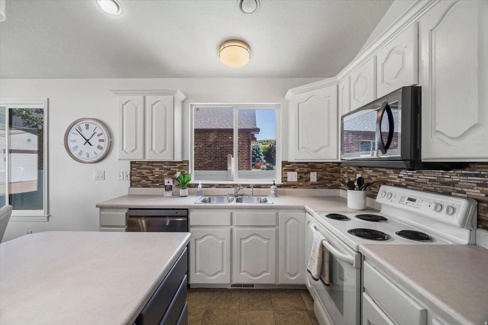 Kitchen featuring white cabinetry, light-toned countertops, and a mosaic tile backsplash