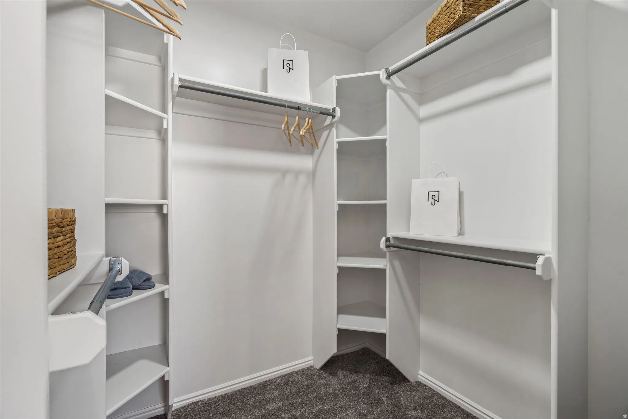 Primary white walk in closet with multiple shelving units and hanging rods